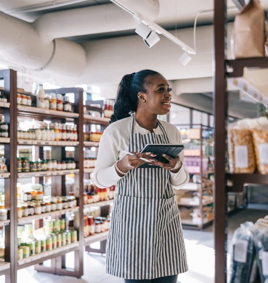 employee at the organic convenience store uses a digital tablet for inventory,