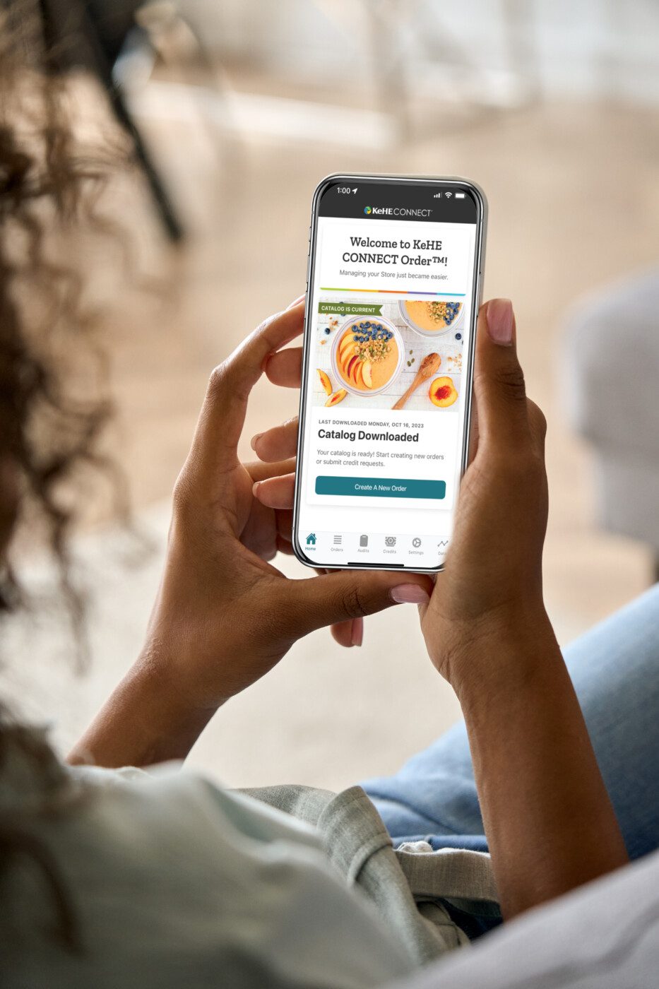 Person holding phone with CONNECT Retailer ordering mobile app